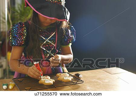 Girl wearing halloween witch costume decorating gingerbread men View Large Photo Image Stock Image - Girl wearing halloween witch costume decorating gingerbread men. Fotosearch