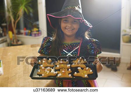 Girl wearing halloween witch costume holding tray of gingerbread men View Large Photo Image Stock Photo - Girl wearing halloween witch costume holding tray of gingerbread men. Fotosearch