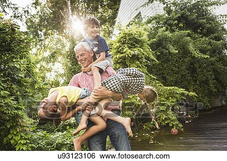 Stock Photograph - Grandfather holding three grandchildren. Fotosearch