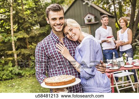 "Group of friends at garden party, young man holding cake" View Large Photo Image Stock Image - "Group of friends at garden party, young man holding cake". Fotosearch