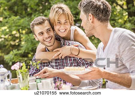 "Group of friends enjoying garden party, young woman hugging young man" View Large Photo Image Stock Photography - "Group of friends enjoying garden party, young woman hugging young man". Fotosearch