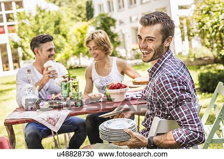 Group of friends setting up garden party View Large Photo Image Stock Image - Group of friends setting up garden party. Fotosearch