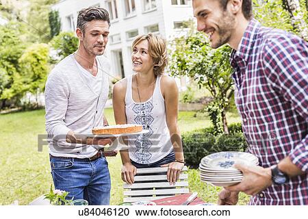 "Group of friends setting up garden party, mid adult man carrying cake" View Large Photo Image Stock Image - "Group of friends setting up garden party, mid adult man carrying cake". Fotosearch