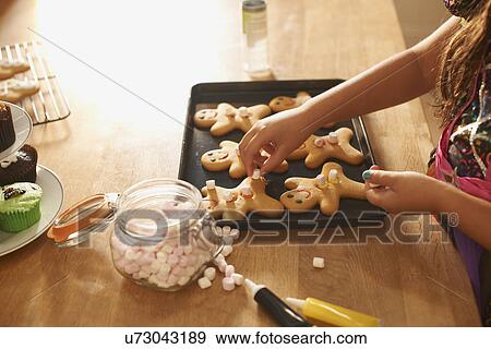 Hands of girl in kitchen decorating gingerbread men for halloween View Large Photo Image Stock Photo - Hands of girl in kitchen decorating gingerbread men for halloween. Fotosearch