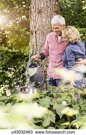 Husband and wife watering plants in garden View Large Photo Image Stock Image - Husband and wife watering plants in garden. Fotosearch