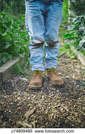 Stock Photo - Legs of boy in dirty knee jeans on allotment. Fotosearch