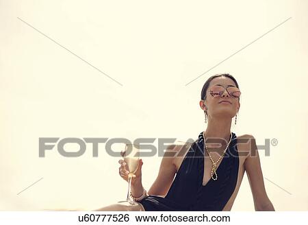 Low angle view of young woman wearing sexy bathing costume drinking champagne View Large Photo Image Stock Photograph - Low angle view of young woman wearing sexy bathing costume drinking champagne. Fotosearch