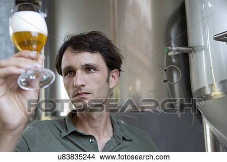 Picture - Male brewer holding glass of beer. Fotosearch