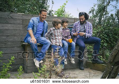 Male friends and sons taking a break on allotment View Large Photo Image Stock Image - Male friends and sons taking a break on allotment. Fotosearch