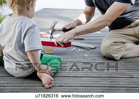 Male toddler watching father make toy boat on pier View Large Photo Image Stock Photograph - Male toddler watching father make toy boat on pier. Fotosearch