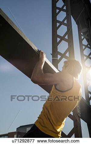 Stock Photo - "Man doing chin ups on bridge, Munich, Bavaria, Germany". Fotosearch