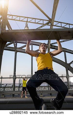 Stock Photography - "Man doing chin-ups on bridge, Munich, Bavaria, Germany". Fotosearch