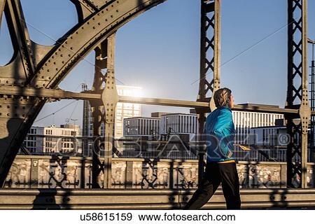 Stock Photo - "Man jogging on bridge, Munich, Bavaria, Germany". Fotosearch