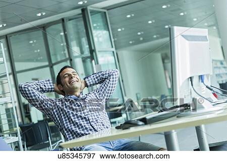 Stock Photo - Man leaning back in chair laughing. Fotosearch