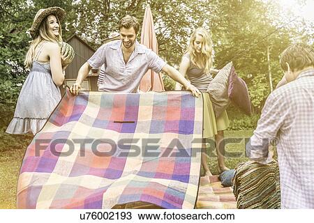 Man opening picnic blanket in garden View Large Photo Image Stock Image - Man opening picnic blanket in garden. Fotosearch