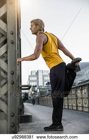 "Man stretching leg on bridge, Munich, Bavaria, Germany" View Large Photo Image Stock Image - "Man stretching leg on bridge, Munich, Bavaria, Germany". Fotosearch