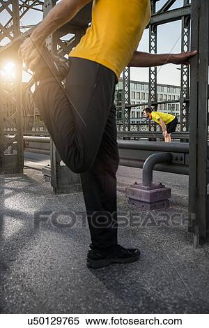 Stock Photography - "Man stretching leg on bridge, Munich, Bavaria, Germany". Fotosearch