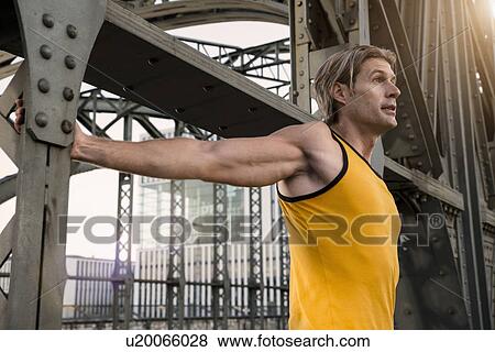 Stock Photo - "Man stretching on bridge, Munich, Bavaria, Germany". Fotosearch