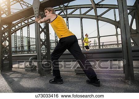 Stock Photograph - "Man stretching on bridge, Munich, Bavaria, Germany". Fotosearch