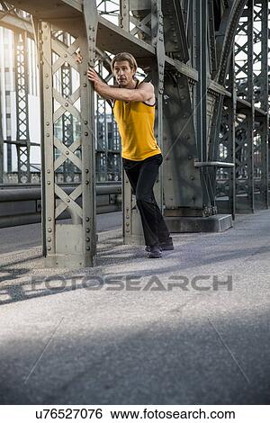 Stock Photograph - "Man stretching on bridge, Munich, Bavaria, Germany". Fotosearch