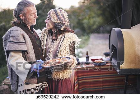 Stock Image - Mature hippy couple with homemade pizza in garden. Fotosearch