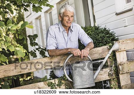 Mature man with watering can in garden View Large Photo Image Stock Photo - Mature man with watering can in garden. Fotosearch