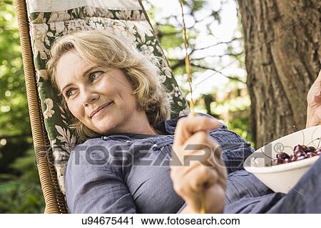 Mature woman relaxing with bowl of cherries on hammock View Large Photo Image Stock Image - Mature woman relaxing with bowl of cherries on hammock. Fotosearch