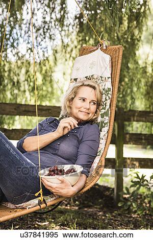Mature woman relaxing with bowl of cherries on hammock View Large Photo Image Stock Photography - Mature woman relaxing with bowl of cherries on hammock. Fotosearch