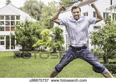 Mid adult man jumping for joy in front of house View Large Photo Image Stock Photo - Mid adult man jumping for joy in front of house. Fotosearch