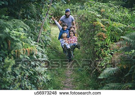 Mid adult man pushing wheelbarrow full of boys in garden View Large Photo Image Stock Photo - Mid adult man pushing wheelbarrow full of boys in garden. Fotosearch