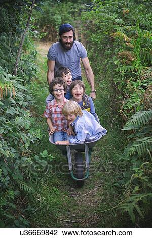 Mid adult man pushing wheelbarrow with smiling boys in garden View Large Photo Image Stock Image - Mid adult man pushing wheelbarrow with smiling boys in garden. Fotosearch