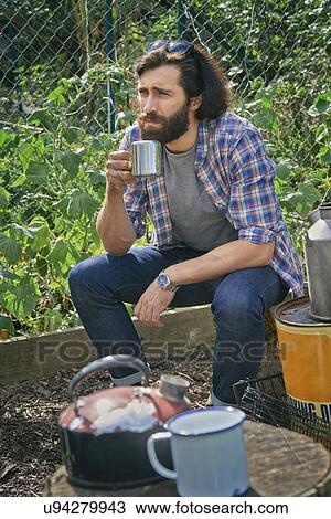 Stock Image - Mid adult man taking a coffee break on allotment. Fotosearch