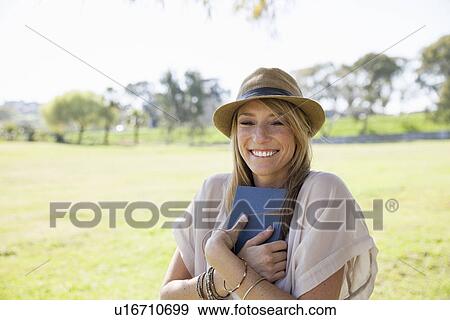 "Mid adult woman in field, holding book" View Large Photo Image Stock Photo - "Mid adult woman in field, holding book". Fotosearch