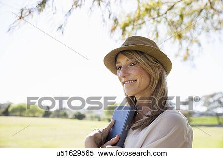 Stock Photography - "Mid adult woman in field, holding book". Fotosearch