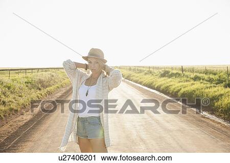 "Mid adult woman on country road, arms behind neck, looking at camera" View Large Photo Image Stock Image - "Mid adult woman on country road, arms behind neck, looking at camera". Fotosearch