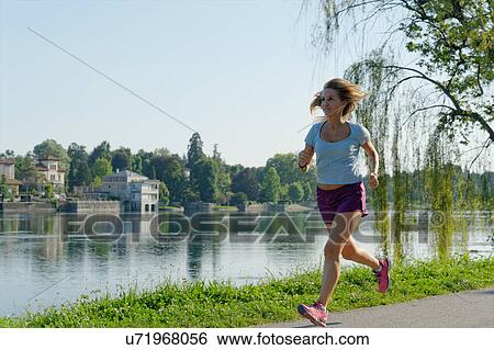 "Mid adult woman resting on grass, beside lake" View Large Photo Image Stock Photograph - "Mid adult woman resting on grass, beside lake". Fotosearch