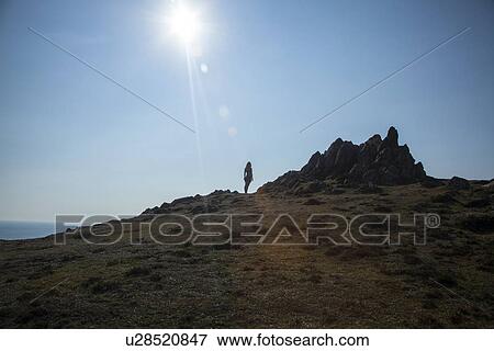 Stock Photo - Mid adult woman standing on cliff edge. Fotosearch
