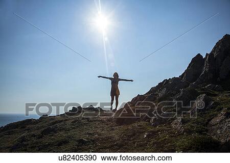 "Mid adult woman standing on cliff edge, arms outstretched" View Large Photo Image Stock Image - "Mid adult woman standing on cliff edge, arms outstretched". Fotosearch