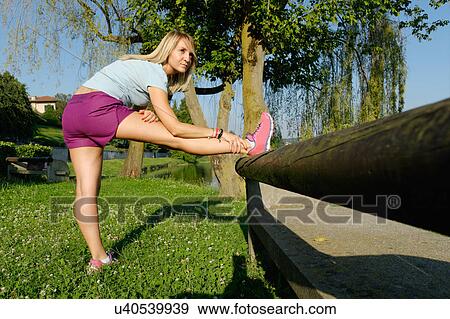 Stock Photo - Mid adult woman stretching against jetty. Fotosearch