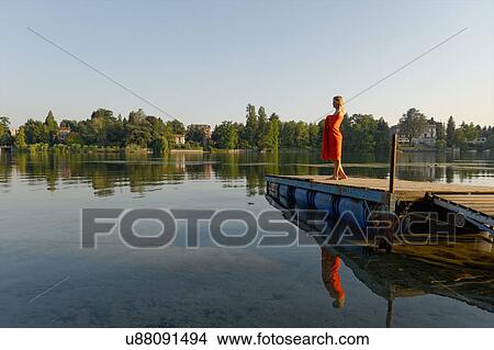 Picture - "Mid adult woman wrapped in towel, standing on jetty". Fotosearch