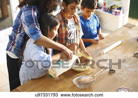 Stock Image - Mother and children baking in kitchen. Fotosearch