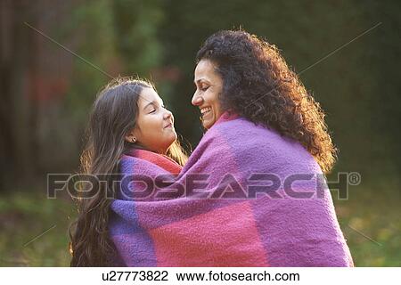 Mother and daughter wrapped in blanket in garden View Large Photo Image Stock Image - Mother and daughter wrapped in blanket in garden. Fotosearch