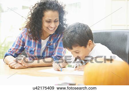 Stock Photo - Mother and son drawing at dining table. Fotosearch