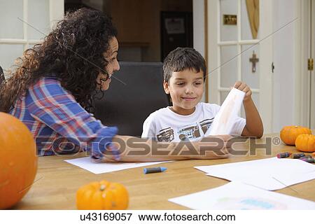 Stock Photo - Mother and son drawing at dining table. Fotosearch
