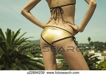 Neck down view of sexy young woman on rooftop wearing gold bikini View Large Photo Image Stock Photo - Neck down view of sexy young woman on rooftop wearing gold bikini. Fotosearch