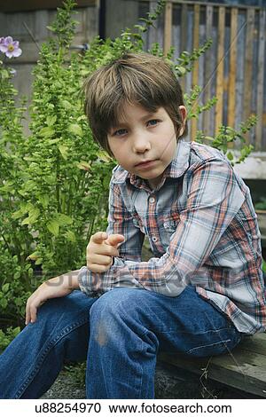 Stock Image - Portrait of boy pointing finger on allotment. Fotosearch