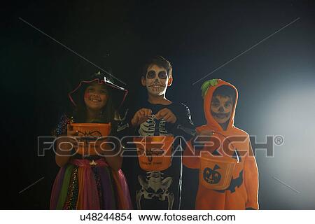 Portrait of brothers and sister wearing halloween costumes holding trick or treat buckets View Large Photo Image Picture - Portrait of brothers and sister wearing halloween costumes holding trick or treat buckets. Fotosearch