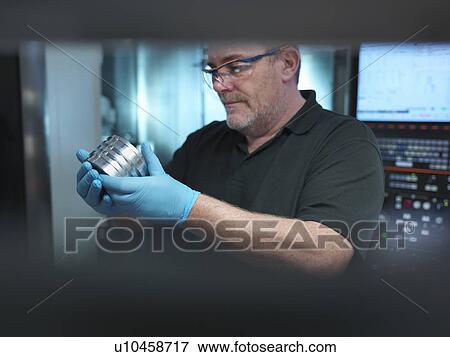 Portrait of engineer holding engineered part at CNC machine in factory View Large Photo Image Stock Photo - Portrait of engineer holding engineered part at CNC machine in factory. Fotosearch