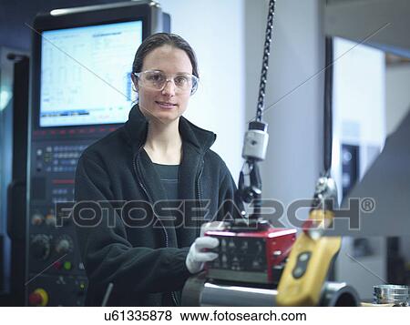 Stock Photo - Portrait of female engineer inspecting part in factory. Fotosearch