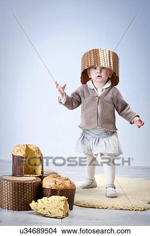 Portrait of female toddler wearing pannetone cake case as hat View Large Photo Image Picture - Portrait of female toddler wearing pannetone cake case as hat. Fotosearch